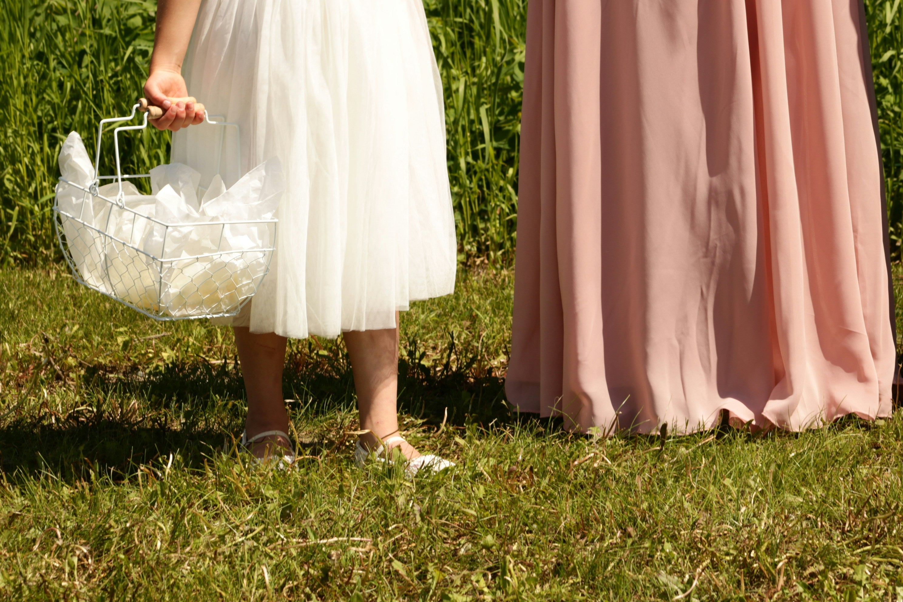 niña acompañando a la novia sobre el pasto con vestido en tonos neutros, ilustrando ideas para bodas de verano como vestidos frescos, flores preservadas y detalles para invitados.