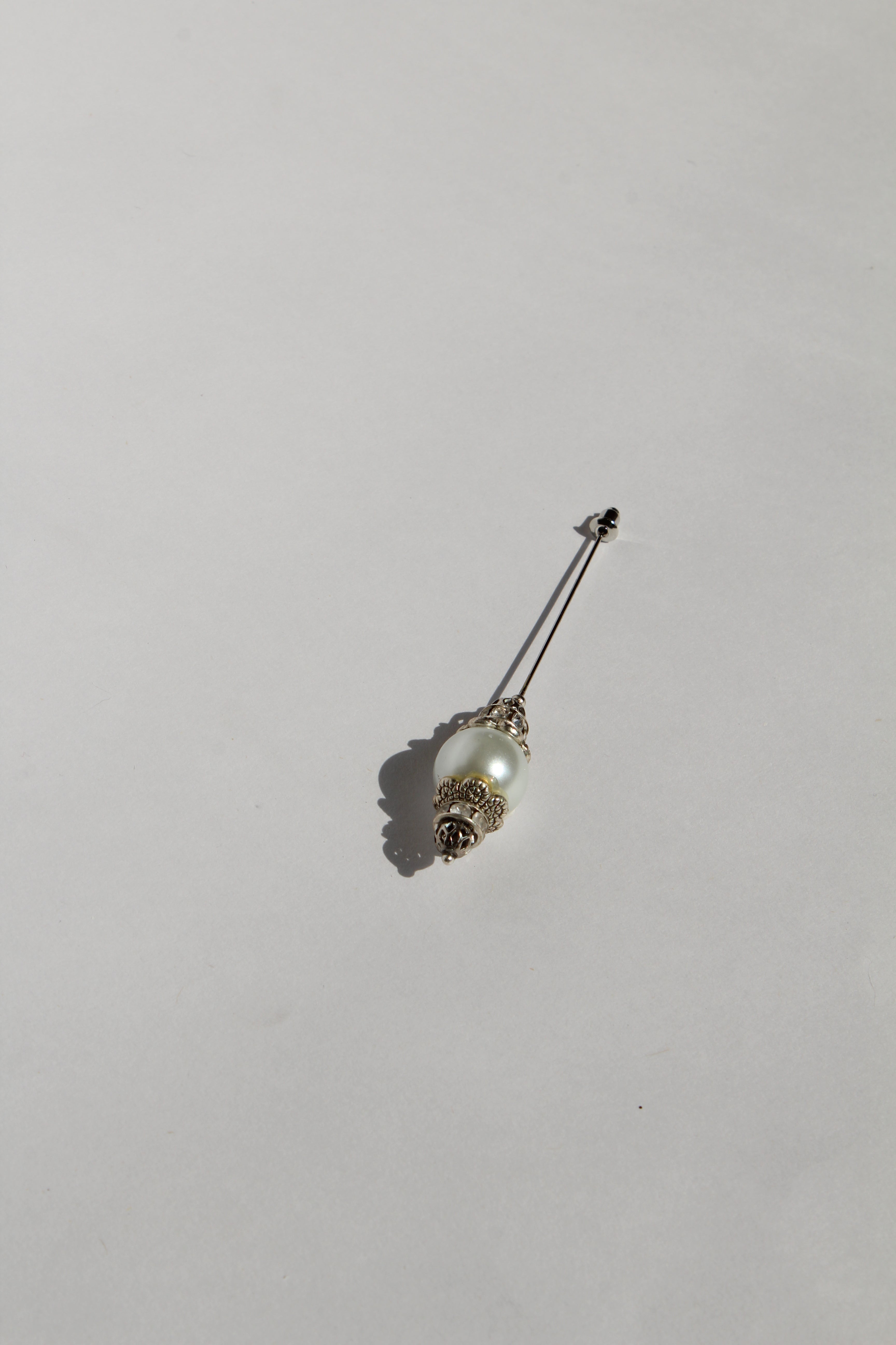 Boutonnière en forma de cetro con una perla